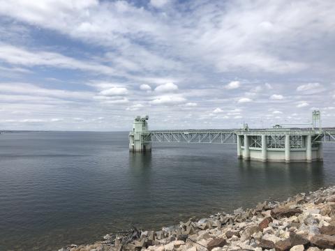 Large metal intake structure extending into Lake McConaughy with rocky shoreline in the foreground.